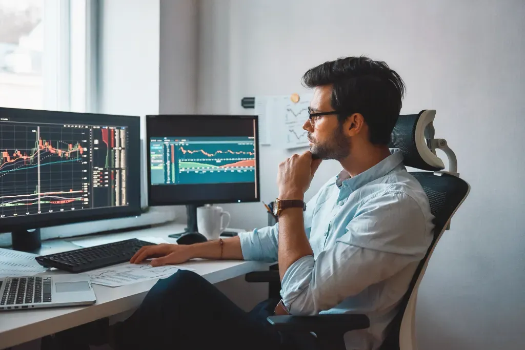 Mężczyzna siedzi przy biurku i zastanawia się, jak zbudować strategię tradingową na TradingView